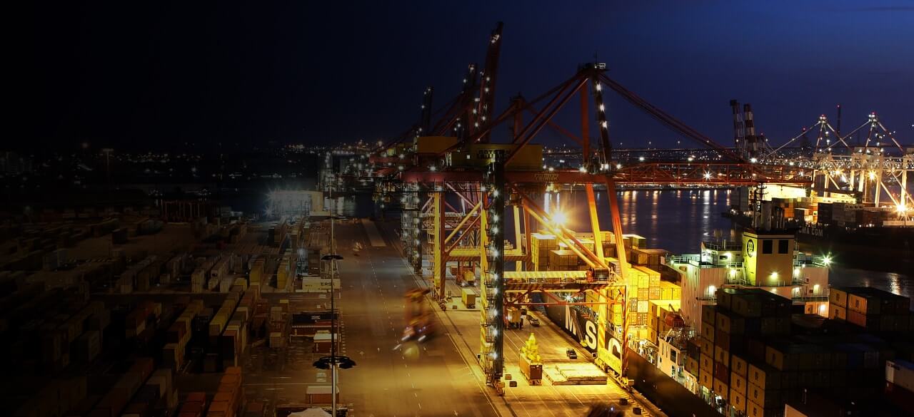 large shipping containers next to port of melbourne container cranes at night